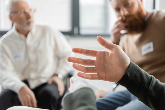 Man sitting near blurred group during alcoholics meeting in rehab center.