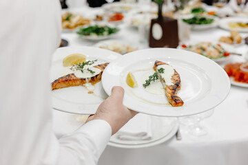 waiter serving food in restaurant, salmon on plate