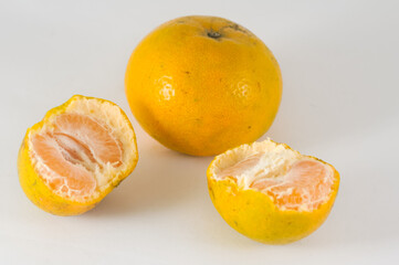 two oranges, one of which is split in half, isolated on a white background