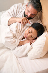 Obraz na płótnie Canvas Guy spending time with his sleeping girlfriend in hotel room