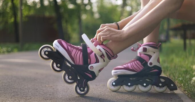 skater girl in park puts rollerblades on her feet