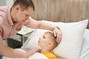 Fototapeta premium Handsome Caucasian dad is soothing the child in the modern hospital