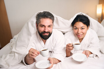 Happy couple drinking coffee in hotel room