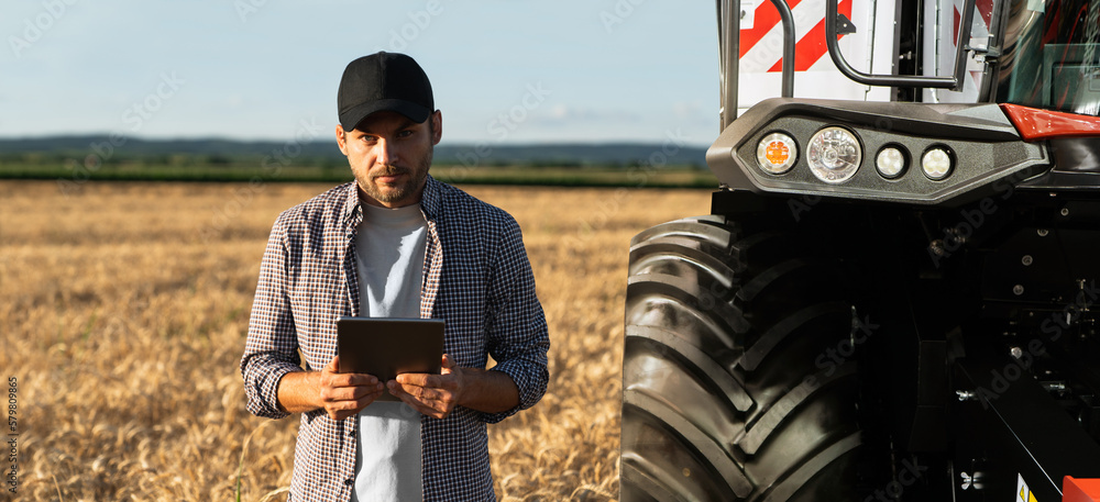 Poster farmer with digital tablet on a background of combine harvester. smart farming concept.