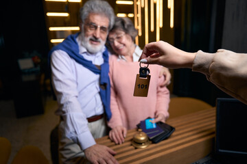 Cute grandparents receive keys to hotel room at reception desk