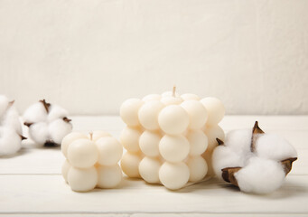 Soy wax candle on a textured table. Interior decor with a handmade burning candle and cotton flowers. Hygge home decoration concept and aromatherapy. Comfort at home.Place for text. Design