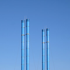 Four painted blue smoke stacks on clear blue sky with no clouds