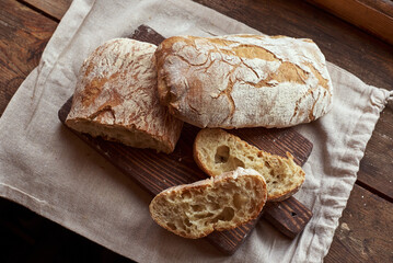 Sliced bread (Ciabatta) on a wooden cutting board and linen bag. Fresh and organic home made food. Top view