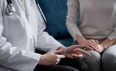 Doctor and patient discussing current health examination while sitting at sofa in clinic office, closeup. Medicine concept.