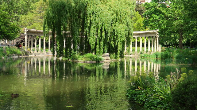 Colonnade corinthienne autour du bassin (naumachie) du parc Monceau &agrave; Paris, et son reflet dans l&rsquo;eau, au milieu de la v&eacute;g&eacute;tation (France)
