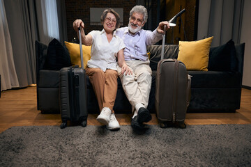 Old couple arrived at hotel, resting on couch