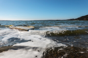 Sunken boat near the shore full of water and sea foam
