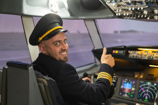 Caucasian bearded man smiling while driving a flight simulator. Pilot in the cockpit showing thumbs up. 