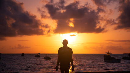 Fototapeta premium Silhouette of man at dawn on the beach