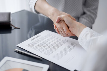 Business people signing contract papers while sitting at the glass table in office, closeup. Partners or lawyers working together at meeting. Teamwork, partnership, success concept.