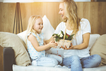Happy mother day. Child daughter congratulates mom and gives her basket of spring flowers. Family concept
