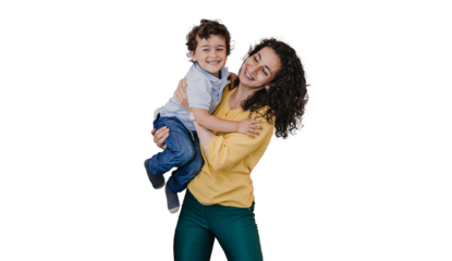 Happy young curly hispanic woman in casual clothes lifts up ;little son smiling standing against transparent background. Cheerful caucasian brunet kid embracing excited mother.