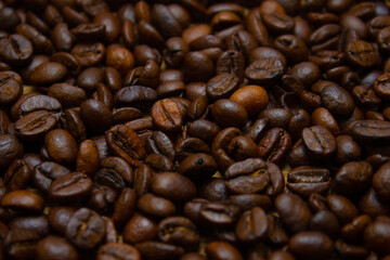 Fascinating background of roasted coffee beans. Fragrant roasted coffee beans are strewn on the table in a large layer. Beautiful background of coffee beans.
