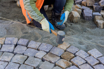 Worker were busy paving sidewalk with granite stones.