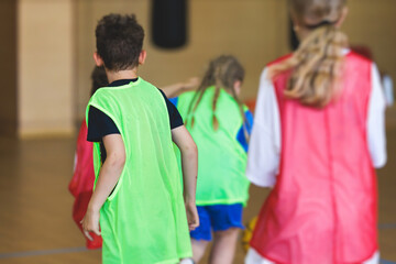 Fototapeta premium Junior teenage school team of kids children play basketball, players in the hall indoor venue court, sports team during the game, playing indoor match game on arena stadium on a wooden parquet floor