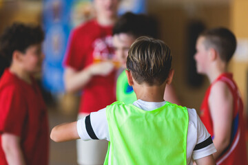 Junior teenage school team of kids children play basketball, players in the hall indoor venue court, sports team during the game, playing indoor match game on arena stadium on a wooden parquet floor