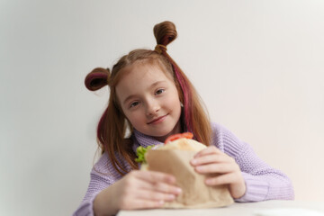 Cute little girl eats sandwich in fast food restaurant. Portrait of pretty white kid eating lunch meal in Greek cafe