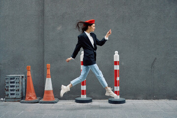 Fashion woman running down the street in front of the city tourist in stylish clothes with red lips and red beret, travel, cinematic color, retro vintage style, late to work, run.