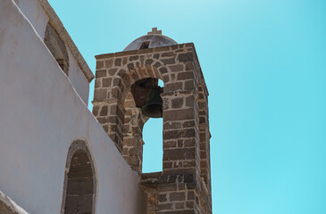 church bell tower view on blue sky background, white stone construction, Greek Island Milos place of attraction - Powered by Adobe