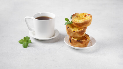 Typical Portuguese custard pies - Pastel de Nata and cup of coffee on white table