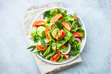 Fresh green salad with leaves and vegetables. Top view at stone table.