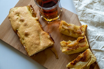 Apple pie and a glass of tea on a wooden board
