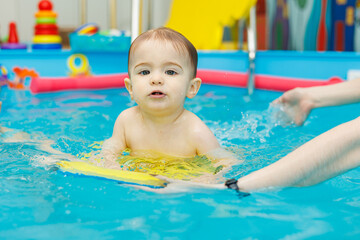 Fototapeta na wymiar Little boy 2 years old are in the pool. Swimming lessons for young children.