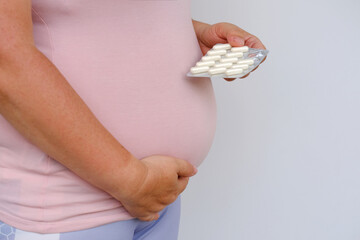 Obraz premium pregnant woman holds drugs, vitamins, hand on belly, concept influence of pharmacology on intrauterine development of fetus, vitamins for pregnant women, healthcare pregnancy, selective focus