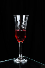 glass goblet with red drink isolated on black background