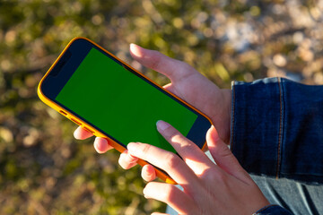 A person holding a phone with a green screen