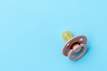 Pink baby pacifier on blue background with copy space, top view, flat lay. Newborn concept