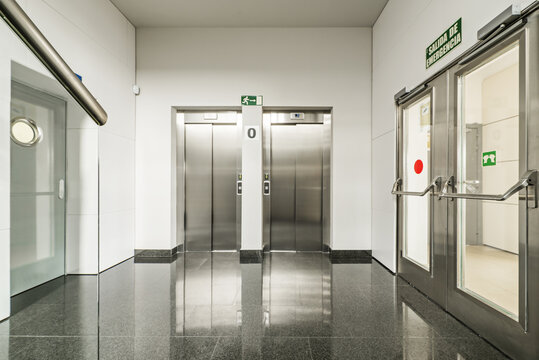 Interior Corridor Of An Office Building Polished Black Granite Floors And Stainless Steel Double Elevator Access Doors