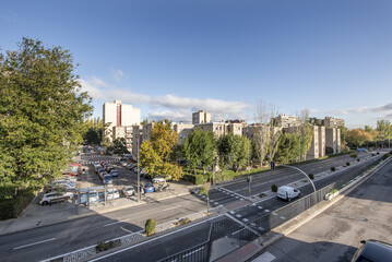 Buildings in a neighborhood with an avenue and trees with grass and hedges between the blocks