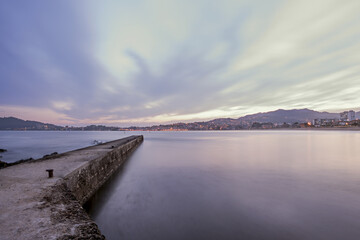 LLong exposure image of a pier at dawn next to a Galician beach