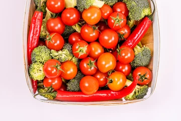Fotobehang A light wooden basket filled with ripe cherry tomatoes, broccoli chunks and red hot chili pepers © Toyakisfoto.photos