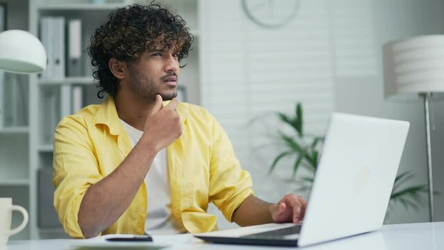 Thoughtful serious worker in office works on laptop computer in moderm office or home Creative designer architect or freelancer think solving problem look for inspiration feeling lack of ideas at work