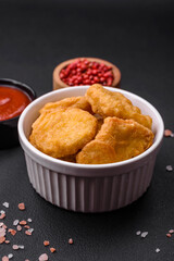 Delicious crispy chicken nuggets with salt and spices on a dark concrete background