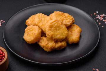 Delicious crispy chicken nuggets with salt and spices on a dark concrete background