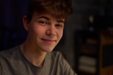 Portrait of teenage boy in dark room, smiling, copy space