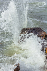 A shot of the sea surf. Splashes of water hitting the stone. Ocean surf among the rocks. Background of the tide.