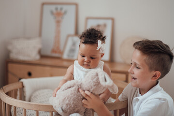 Portrait of candid friendly interracial family white boy with little swarthy baby sister at home