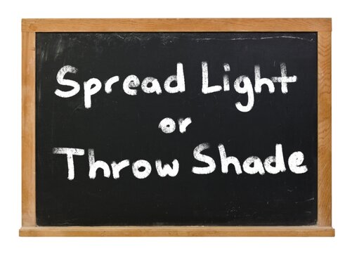 Spread light or throw shade written in white chalk on a black chalkboard isolated on white