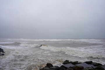 View of stormy ocean water fronts with waves breaking on rocks