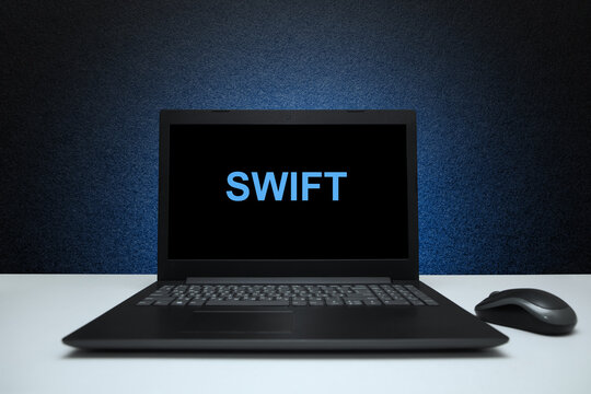 Swift text on laptop screen on textured black background with blue light. Learn swift programming language, computer courses, training.