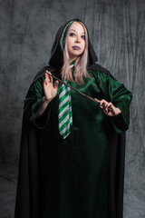 Magic teacher in a green robe with a magic wand, studio gray background